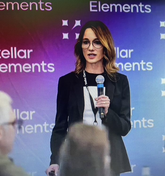Jeannette Michels speaking on stage with a microphone
